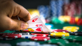 Gambling Hand Holding Poker Cards and Money Coins ChipsGambling Hand Holding Poker Cards and Money Coins Chips